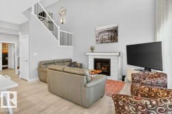 Beautiful open-to-below great room with 18' ceilings, large, bright windows, and a cozy feature gas fireplace. - 