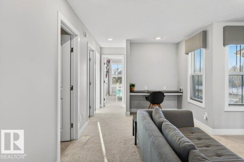 2nd floor landing at the top of the stairs, looking towards the front of the home with a bonus room, workspace/desk area, bedrooms, laundry, and bathroom. - 1909 Davidson Wynd, Edmonton, AB - Indoor