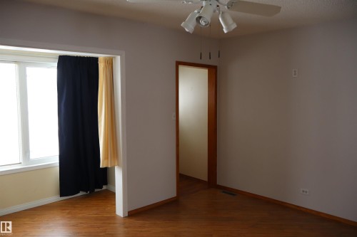 Empty room featuring a ceiling fan and dark wood finished floors - 5109 55 Street, Barrhead, AB - Indoor Photo Showing Other Room