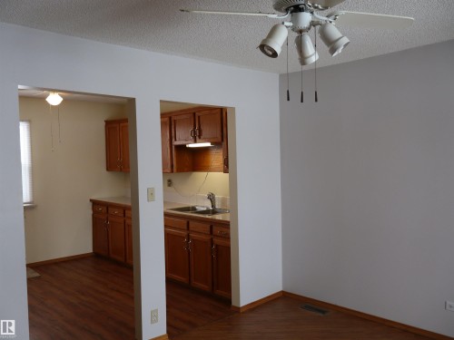 Kitchen featuring a ceiling fan, wood finish cabinets, a textured ceiling, light countertops, and dark wood-type flooring - 5109 55 Street, Barrhead, AB - Indoor Photo Showing Other Room