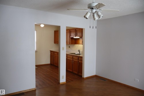 Kitchen with wood finish cabinets, dark wood-type flooring, a textured ceiling, light countertops, and ceiling fan - 5109 55 Street, Barrhead, AB - Indoor