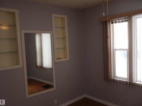 Empty room featuring healthy amount of natural light, dark wood-type flooring, and built in features - 5109 55 Street, Barrhead, AB - Indoor Photo Showing Other Room