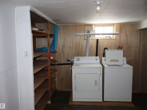 Laundry room with washer and clothes dryer, wooden walls, and dark wood-style floors - 5109 55 Street, Barrhead, AB - Indoor Photo Showing Laundry Room