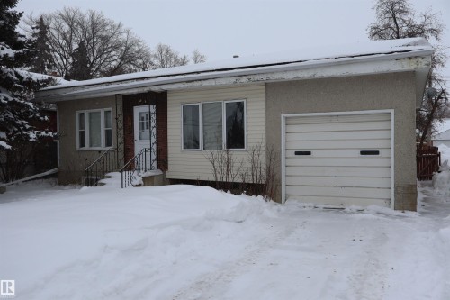 Bungalow-style house featuring roof mounted solar panels, an attached garage, and stucco siding - 5109 55 Street, Barrhead, AB - Outdoor