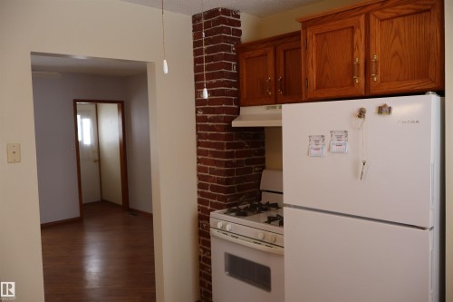 Kitchen with white appliances, dark wood-style flooring, and wood finish cabinets - 5109 55 Street, Barrhead, AB - Indoor Photo Showing Kitchen