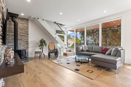 Living area featuring a wood stove, light wood finished floors, and recessed lighting - 14412 80 Avenue Nw, Edmonton, AB - Indoor Photo Showing Living Room With Fireplace