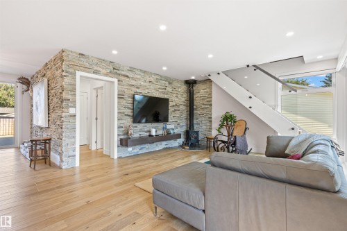 Living area featuring light wood-type flooring, a wood stove, and recessed lighting - 14412 80 Avenue Nw, Edmonton, AB - Indoor Photo Showing Living Room