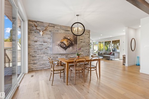 Dining area with a chandelier, light wood finished floors, and an accent wall - 14412 80 Avenue Nw, Edmonton, AB - Indoor Photo Showing Dining Room