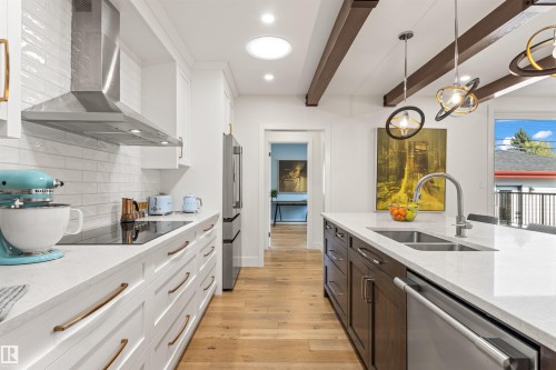 Two tone kitchen featuring two tone color scheme, light stone countertops, stainless steel appliances, light wood-type flooring, and pendant lighting - 14412 80 Avenue Nw, Edmonton, AB - Indoor Photo Showing Kitchen With Double Sink With Upgraded Kitchen