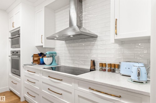 Kitchen with light stone countertops, white cabinets, black electric cooktop, and tasteful backsplash - 14412 80 Avenue Nw, Edmonton, AB - Indoor Photo Showing Kitchen