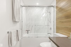 Full bath featuring combined bath / shower with glass door, vanity, and wooden walls - 