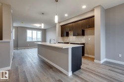 Kitchen featuring dark wood finish cabinetry, light wood-style flooring, a center island with sink, and modern cabinets - 
