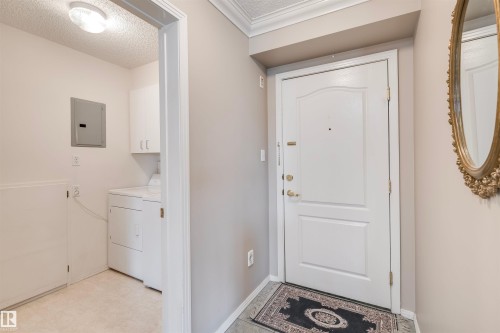 Entryway featuring a textured ceiling, electric panel, tile patterned floors, and independent washer and dryer - 209 17150 94A Avenue, Edmonton, AB - Indoor Photo Showing Laundry Room