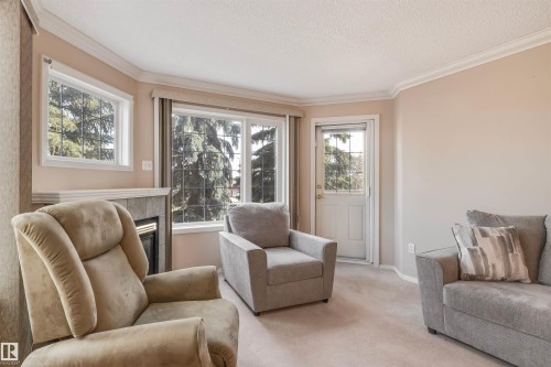 Sitting room featuring crown molding, carpet flooring, a fireplace, and a textured ceiling - 209 17150 94A Avenue, Edmonton, AB - Indoor Photo Showing Living Room