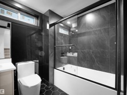 Full bath featuring vanity, combined bath / shower with glass door, and dark tile patterned flooring - 
