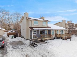 Snow covered back of property featuring a chimney and covered porch - 