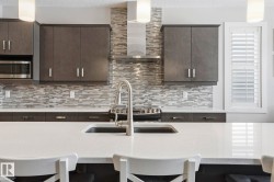 Kitchen featuring a kitchen bar, pendant lighting, light stone countertops, and a textured ceiling - 