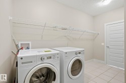 Laundry room with washing machine and dryer, a textured ceiling, and light tile patterned flooring - 