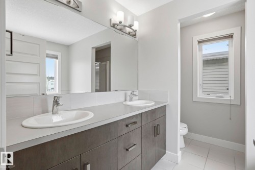 Bathroom with double vanity, a stall shower, and light tile patterned floors - 1915 77 Street Sw, Edmonton, AB - Indoor Photo Showing Bathroom