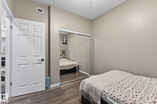 Bedroom featuring a textured ceiling, dark wood-style flooring, and a closet - 103 8108 109 Street, Edmonton, AB - Indoor Photo Showing Bedroom