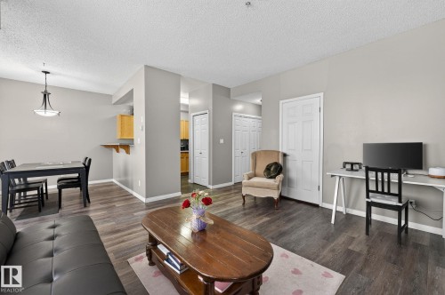 Living area featuring dark wood-type flooring, a textured ceiling, and an office area - 103 8108 109 Street, Edmonton, AB - Indoor Photo Showing Living Room