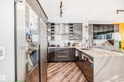 Kitchen featuring stainless steel appliances, a peninsula, light stone countertops, track lighting, and backsplash - 