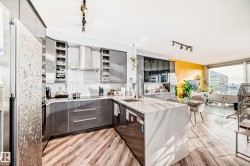Kitchen featuring a peninsula, track lighting, stainless steel appliances, light stone countertops, and gray cabinetry - 