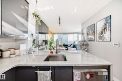 Kitchen with stainless steel dishwasher, light stone countertops, gray cabinets, backsplash, and rail lighting - 