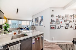 Kitchen featuring dishwasher, light wood-style flooring, light stone countertops, open floor plan, and gray cabinets - 
