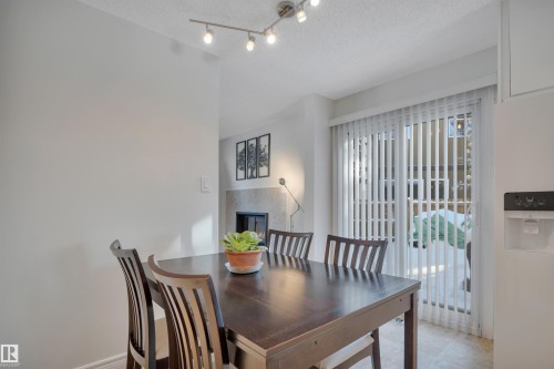 Dining area featuring a textured ceiling and a fireplace - 7075 32 Avenue, Edmonton, AB - Indoor Photo Showing Dining Room