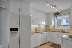 Kitchen featuring white appliances, white cabinetry, a textured ceiling, decorative backsplash, and light stone counters - 