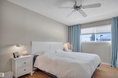 Bedroom with light wood-type flooring, a textured ceiling, and a ceiling fan - 7075 32 Avenue, Edmonton, AB - Indoor Photo Showing Bedroom