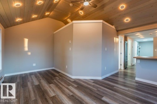Empty room featuring a ceiling fan, a vaulted wood ceiling, recessed lighting, dark wood finished floors, and a baseboard radiator - 4713 48 Avenue, Wetaskiwin, AB - Indoor Photo Showing Other Room
