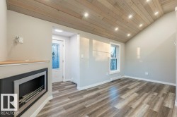 Unfurnished living room with recessed lighting, a vaulted wood ceiling, wood finished floors, a fireplace, and a baseboard heating unit - 