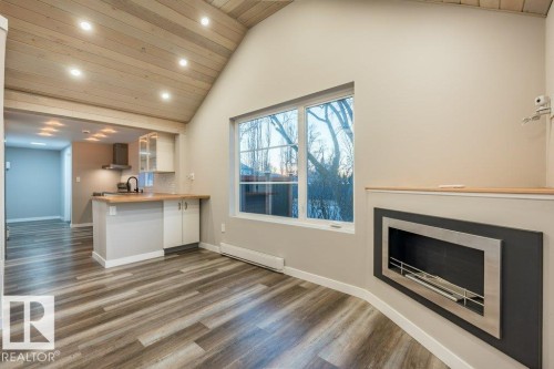Kitchen with glass insert cabinets, a vaulted wood ceiling, recessed lighting, dark wood-type flooring, and a baseboard heating unit - 4713 48 Avenue, Wetaskiwin, AB - Indoor With Fireplace