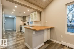 Kitchen featuring glass insert cabinets, baseboard heating, a peninsula, dark wood-style flooring, and stainless steel range with electric stovetop - 