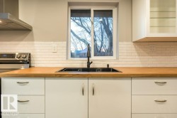 Kitchen featuring white cabinetry, electric range oven, and wall chimney exhaust hood - 