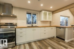 Kitchen featuring stainless steel appliances, glass fronted cabinets, white cabinets, a peninsula, and recessed lighting - 
