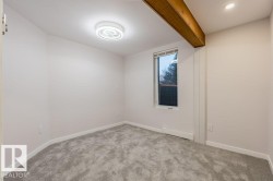 Unfurnished room featuring beam ceiling, light colored carpet, and a baseboard radiator - 