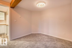 Unfurnished room with light colored carpet and beamed ceiling - 