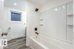 Bathroom featuring a baseboard heating unit, shower / bath combination, and dark wood finished floors - 