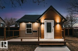 View of front of house with a deck, roof with shingles, and an outbuilding - 