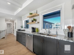 Kitchen featuring light stone counters, open shelves, light wood-style flooring, dishwasher, and beam ceiling - 