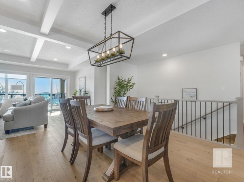 Dining room with a textured ceiling, light wood-style floors, beamed ceiling, and suspended lighting - 209 55101 Ste. Anne Trail, Rural Lac Ste. Anne County, AB - Indoor Photo Showing Dining Room