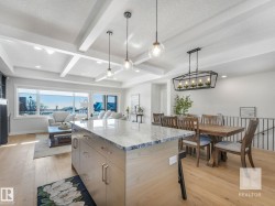 Kitchen with light stone counters, light wood-style floors, decorative light fixtures, a kitchen island, and beam ceiling - 