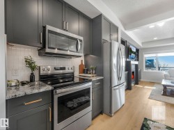 Kitchen with stainless steel appliances, a textured ceiling, light wood-style floors, a lit fireplace, and light stone countertops - 