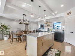 Kitchen with light stone counters, decorative light fixtures, a center island, light wood finished floors, and a textured ceiling - 
