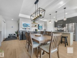 Dining space with light wood-type flooring, a chandelier, a textured ceiling, and a tray ceiling - 