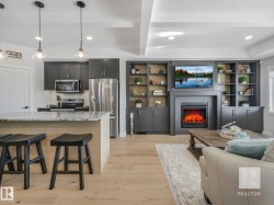 Living area with a textured ceiling, light wood-style flooring, recessed lighting, a tiled fireplace, and beam ceiling - 