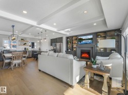 Living area with light wood finished floors, built in shelves, beamed ceiling, a lit fireplace, and recessed lighting - 